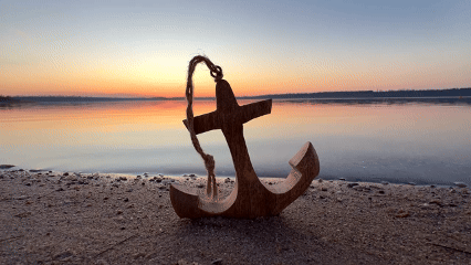 colorful sunset at the sea with wooden anchor