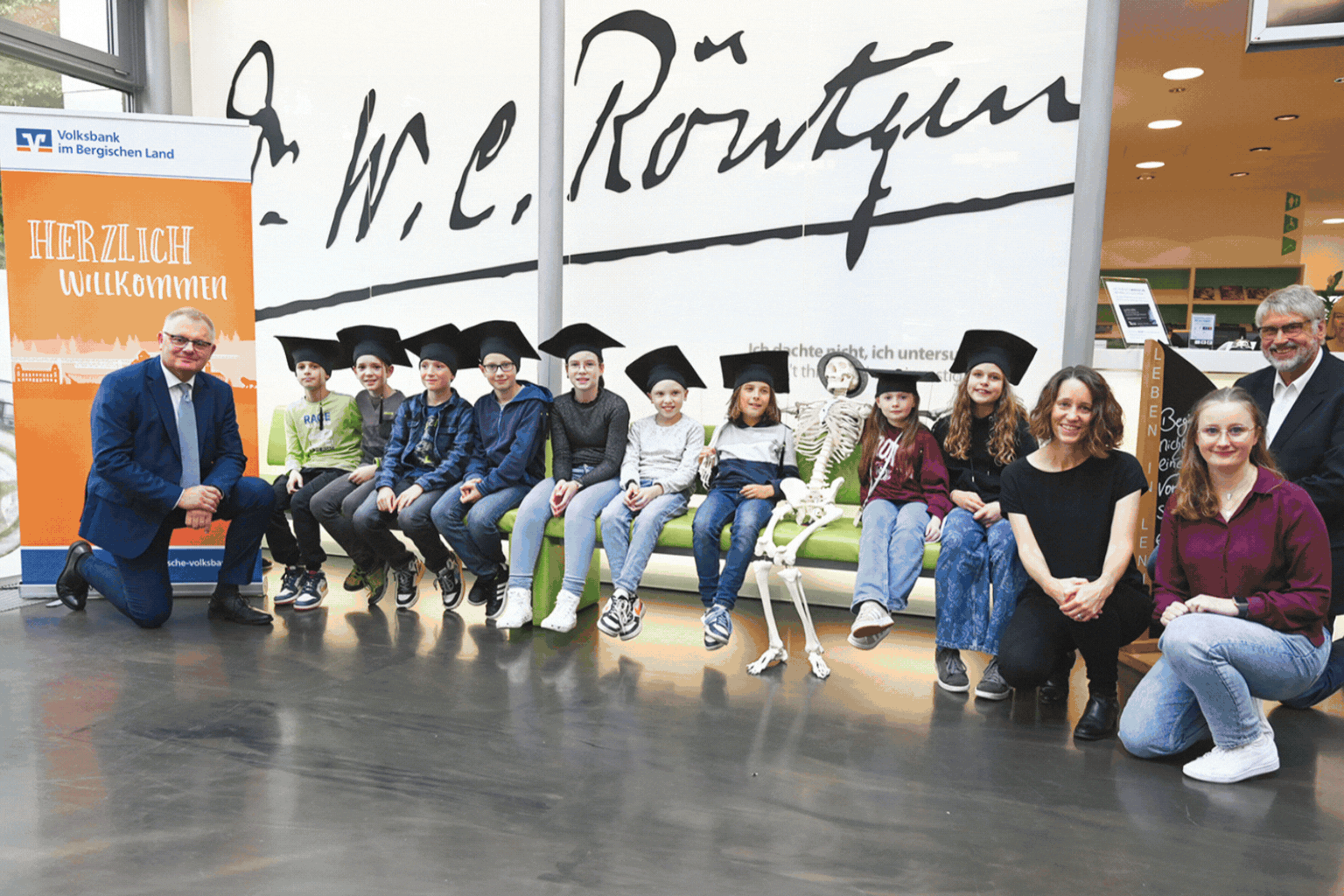Kinder mit Bachelorhüten sitzen auf Sofa im Röntgen Museum