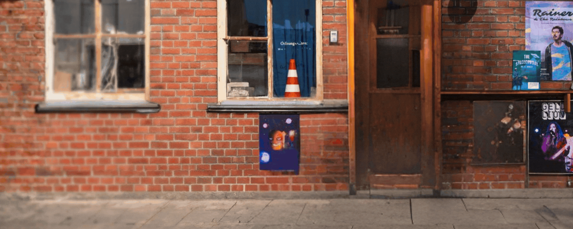 Mann mit Helm und orangefarbener Jacke sitzt auf einem blauen Moped und lächelt in die Kamera