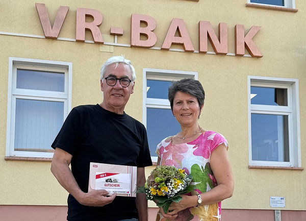 Ein Mann und eine Frau stehen gemeinsam vor einem modernen VR-Bankgebäude