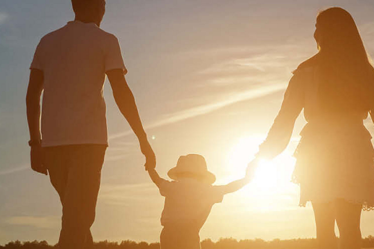 Eine Familie mit zwei Kindern gehen auf einen Sonnenuntergang zu