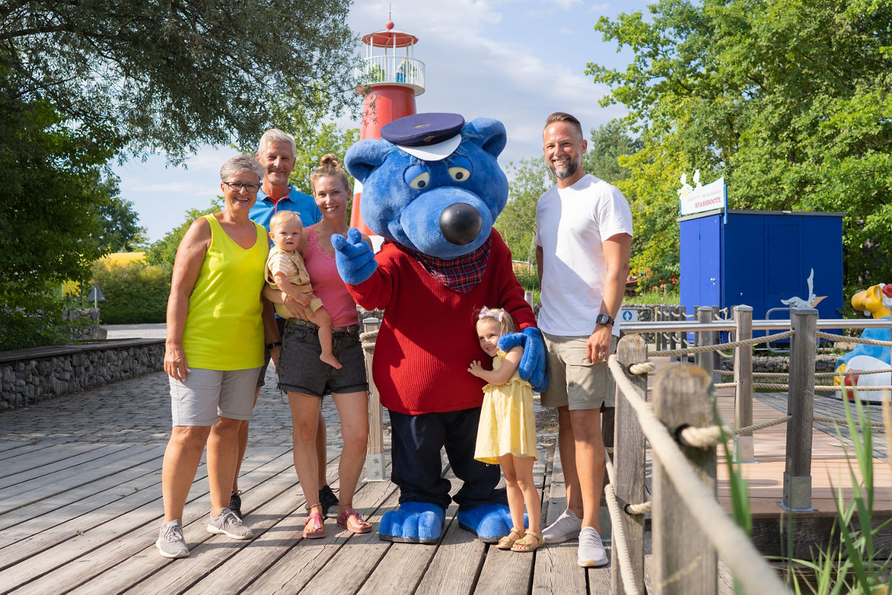 Käptn Blaubär mit einer Familie am Eingang des Ravensburger Spielelands