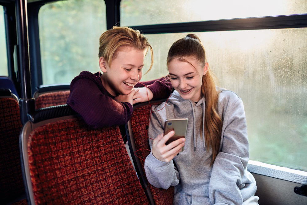 Zwei Jugendliche schauen auf ein Mobiltelefon