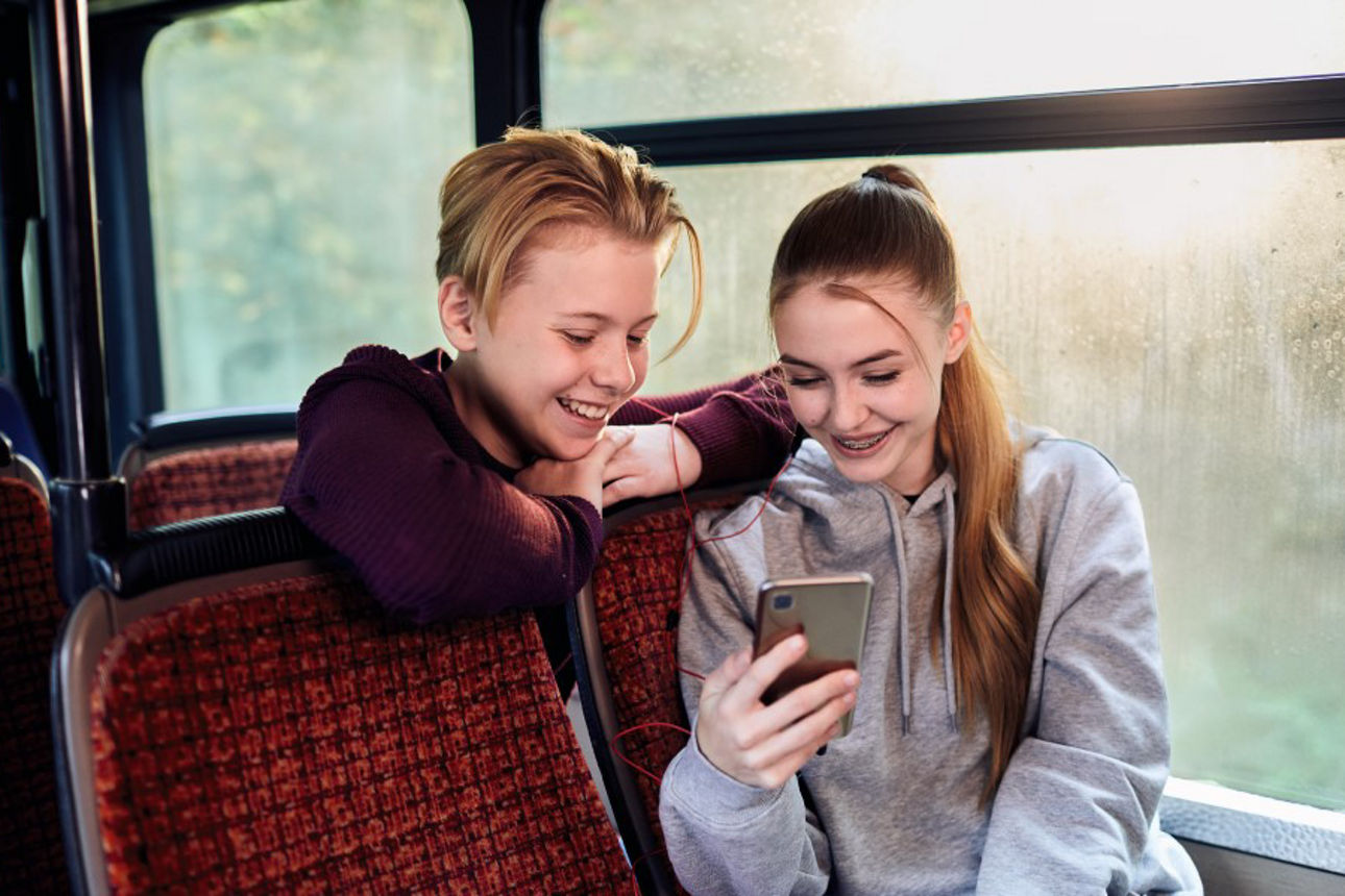 Zwei Jugendliche schauen auf ein Mobiltelefon