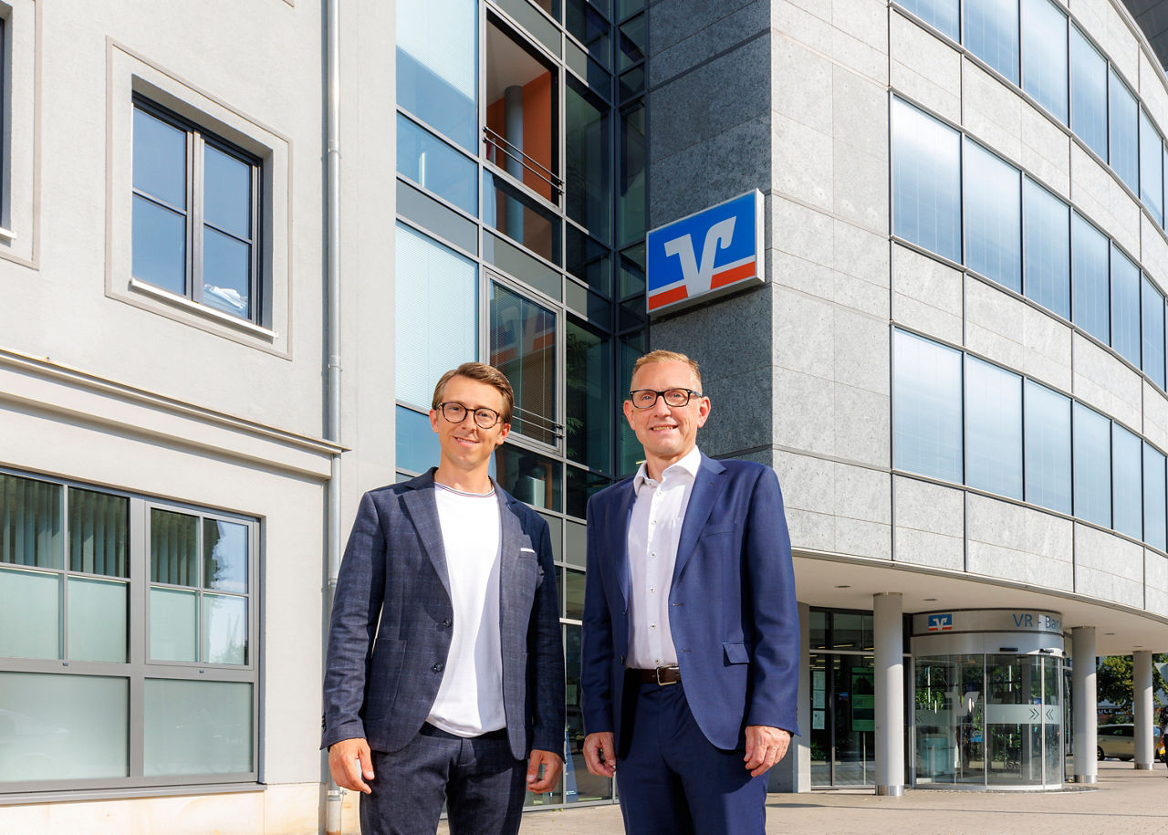 Zwei Männder stehen vor einem Bankgebäude