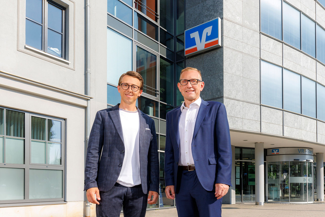 Zwei Männder stehen vor einem Bankgebäude