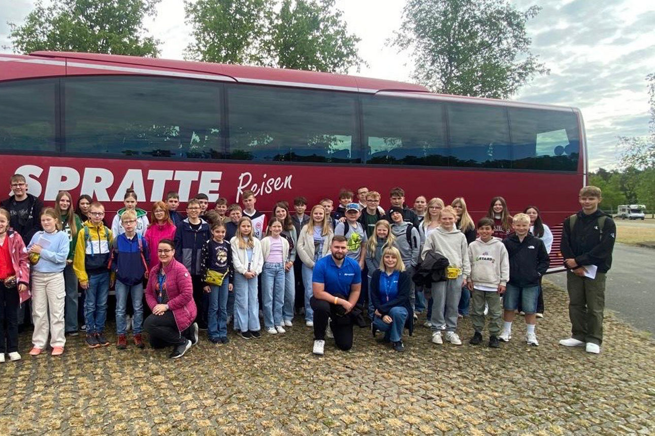 Eine Gruppe von Kinder steht gemeinsam vor einem roten Reisebus