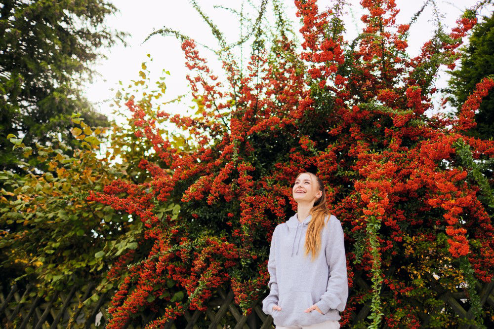 Ein glücklicher Jugendliche neben roten Blumen