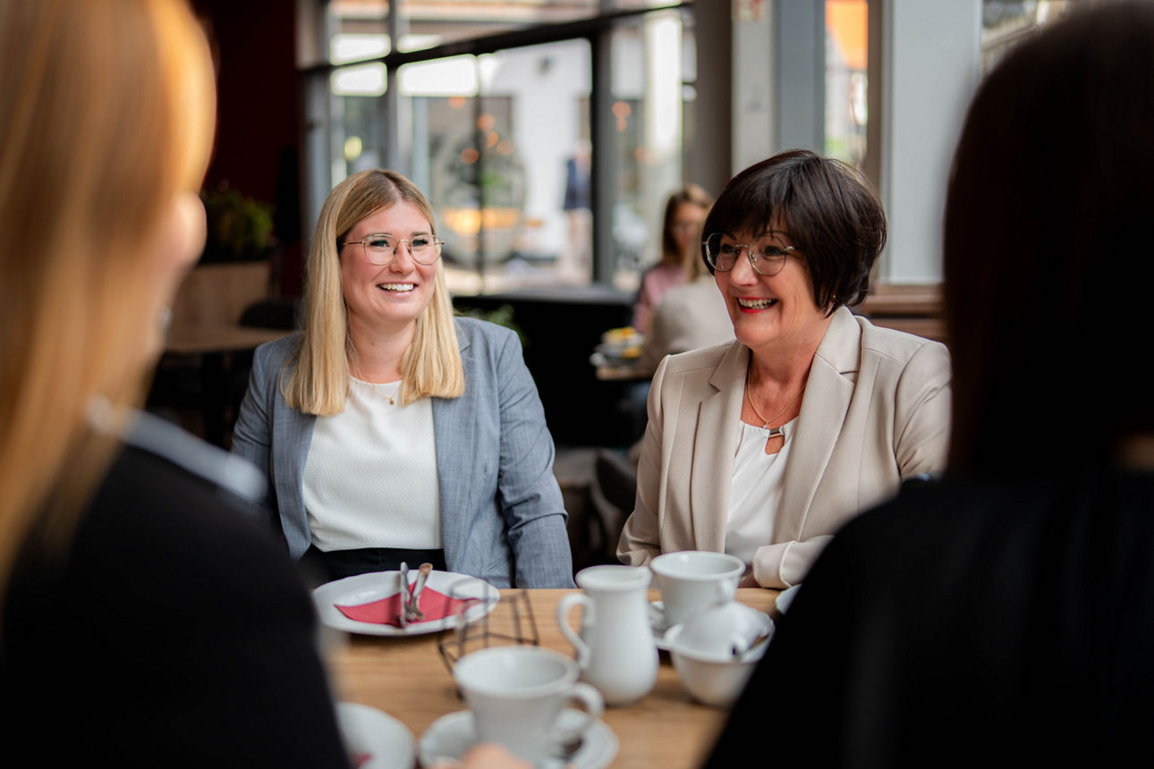 Eine Gruppe von Frauen, die sich an einem Cafétisch ungezwungen unterhält.