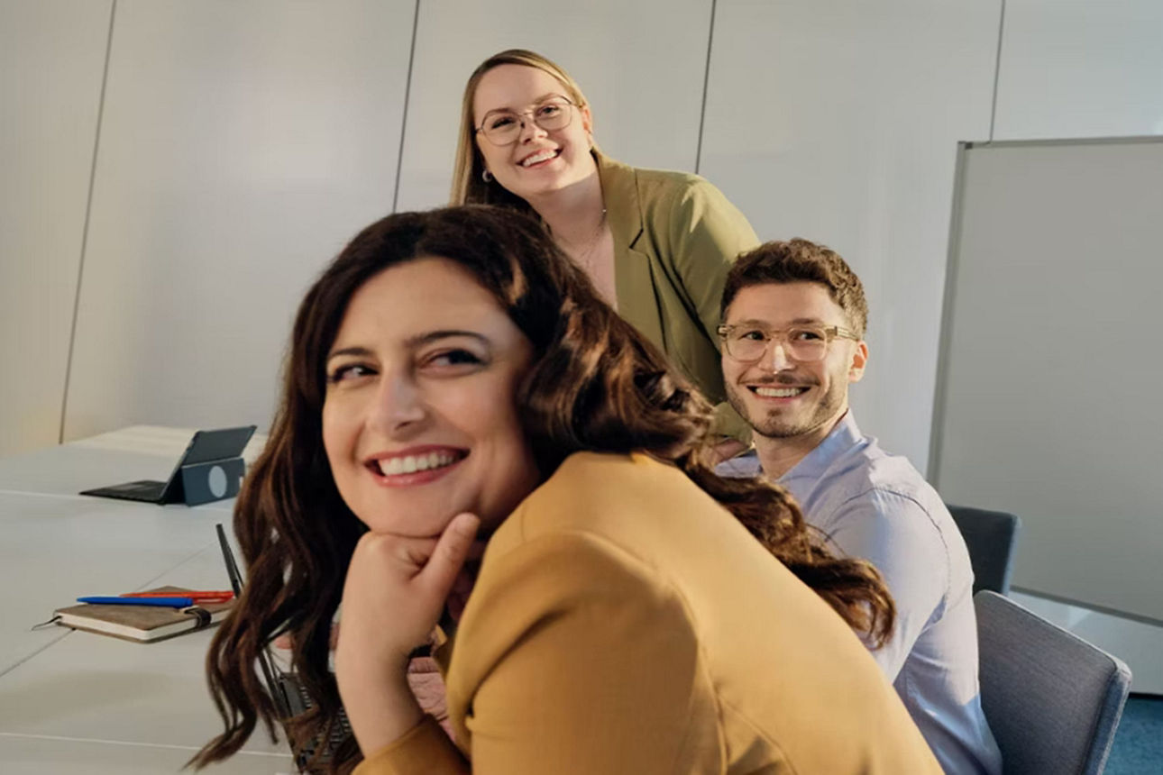 Zwei Frauen und ein Mann lächeln und schauen in die Kamera.