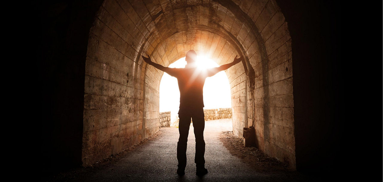 Person steht in einem Tunnel und die Sonne scheint hinein