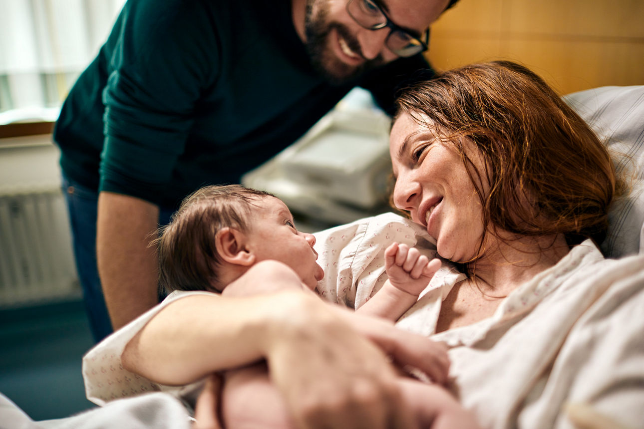 Eine Frau liegt im Krankenhaus mit einem Baby im Arm