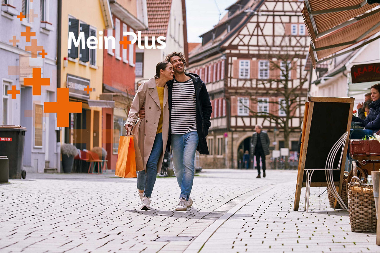 Paar geht Arm in Arm in einer Altstadt spazieren. Logo MeinPlus