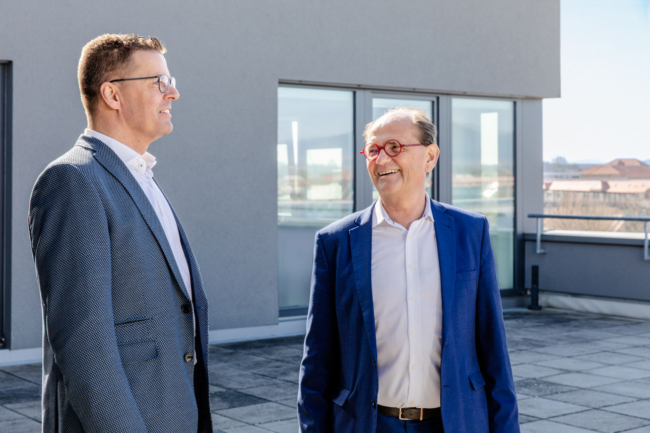 Zwei Männer im Gespräch auf einer Dachterrasse