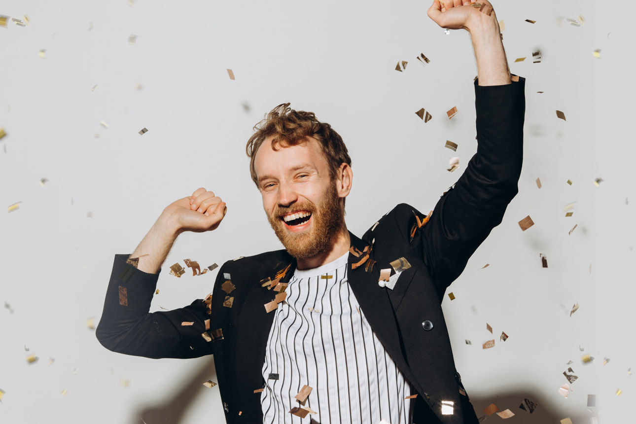 Mann tanzt mit Konfetti im Hintergrund
