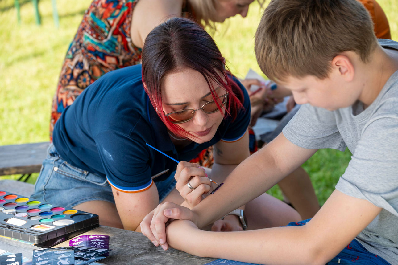Beim Kinderschminken - unsere Mitarbeiterin bemalt den Arm eines Kindes