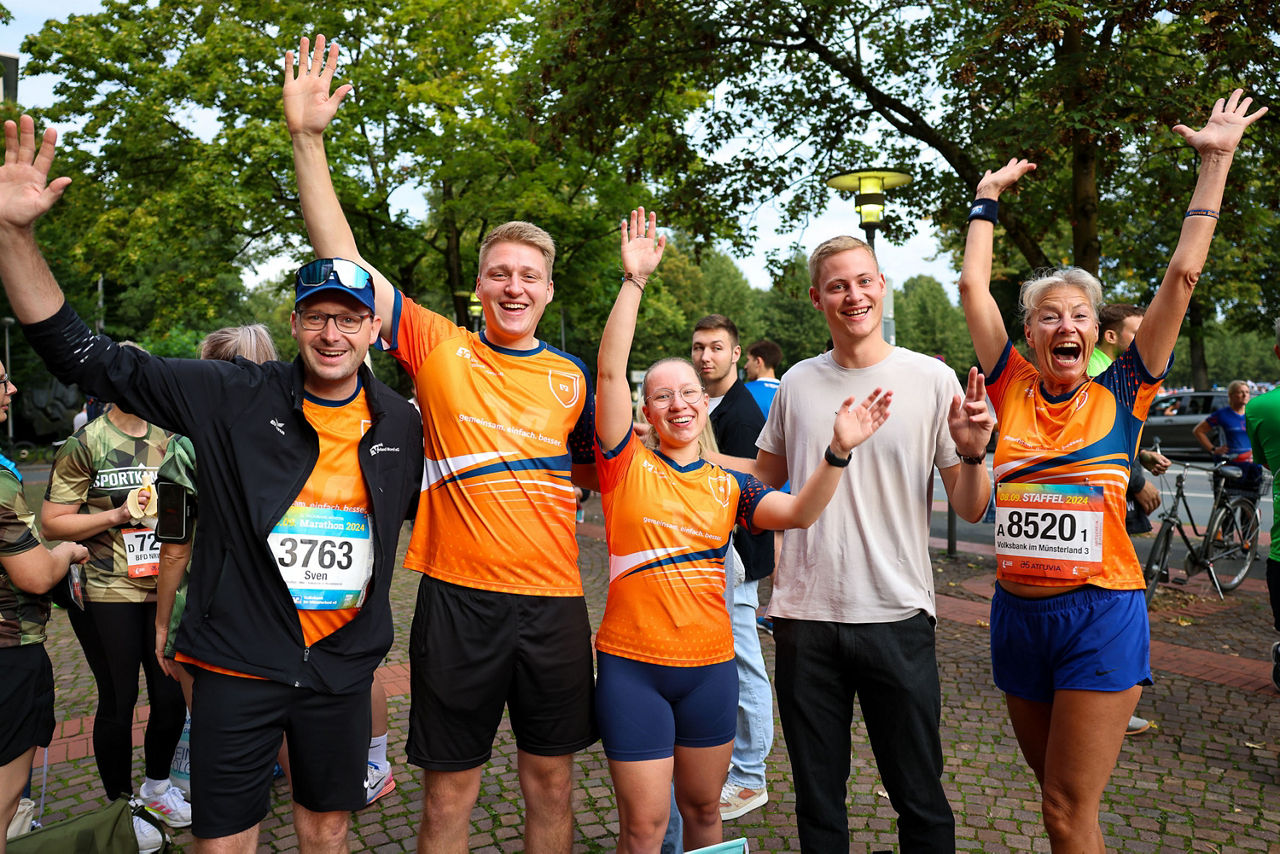 Ein Team der Volksbank im Münsterland hat am Staffellauf teilgenommen und jubelt in orangenen Trikots