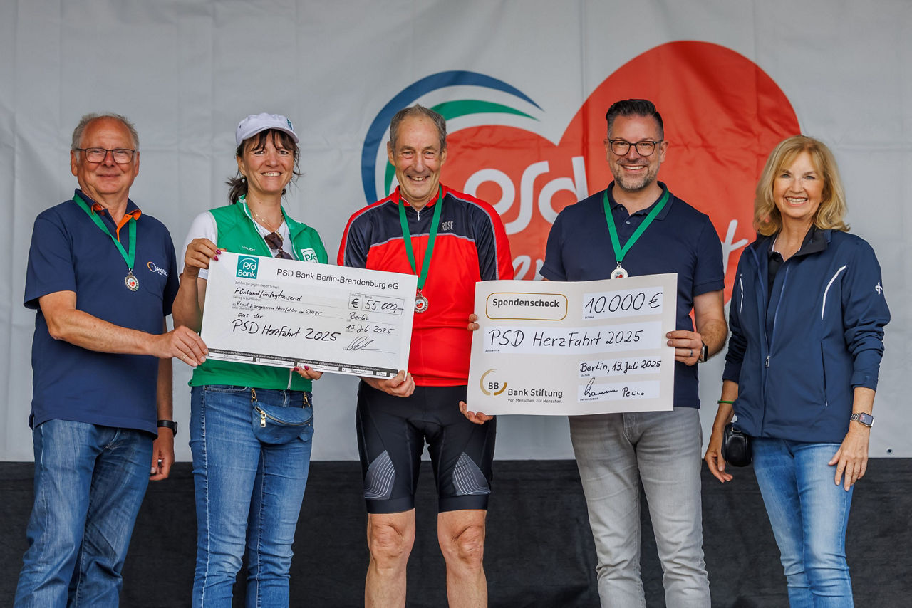 Organisatoren der Herzfahrt halten Spendenscheck in Höhe von 65.000 Euro
