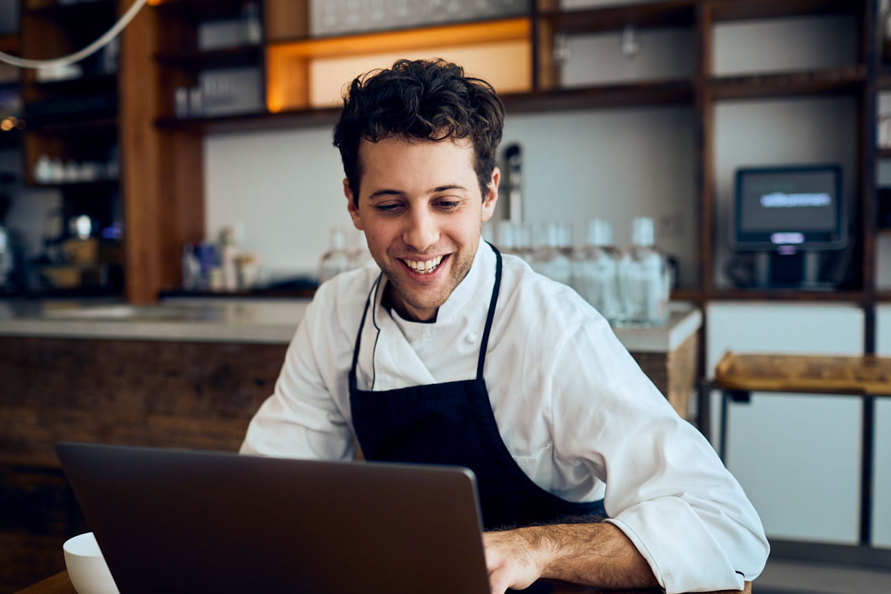 Glücklicher Koch vor Laptop