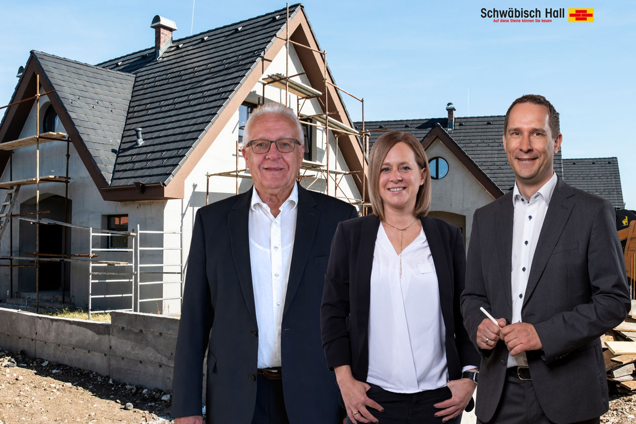 Drei Personen vor einem Hausbau