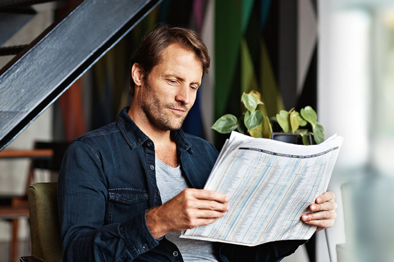 Ein Mann mittleren Alters, der eine Zeitung liest