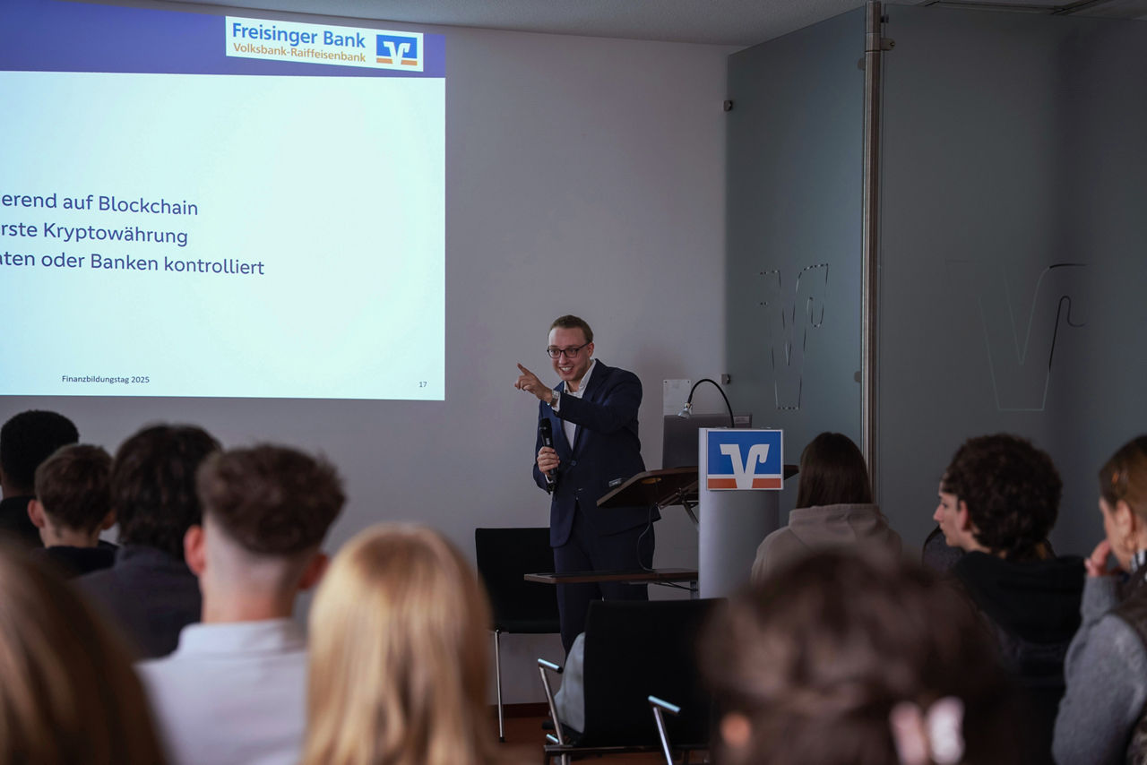 Jannis Dietl spricht vor Schüler*innen, die von hinten zu sehen sind. An der Wand hinter ihm ein Teil seiner Präsentation.