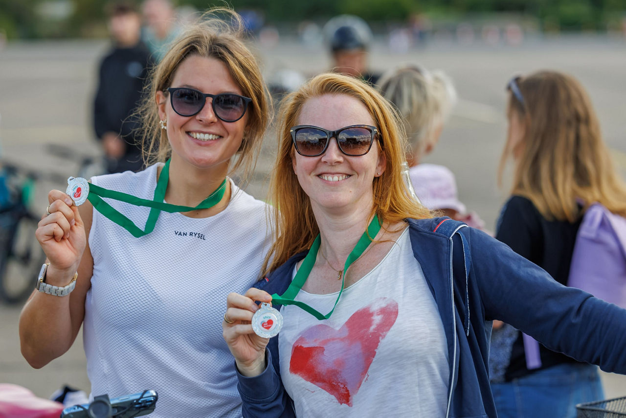 zwei junge Radfahrerinnen halten Medaille in die Kamera