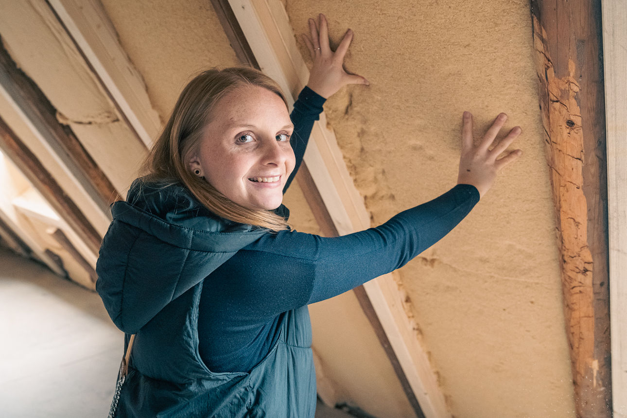 Person prüft die Isolierung eines Dachbodens.