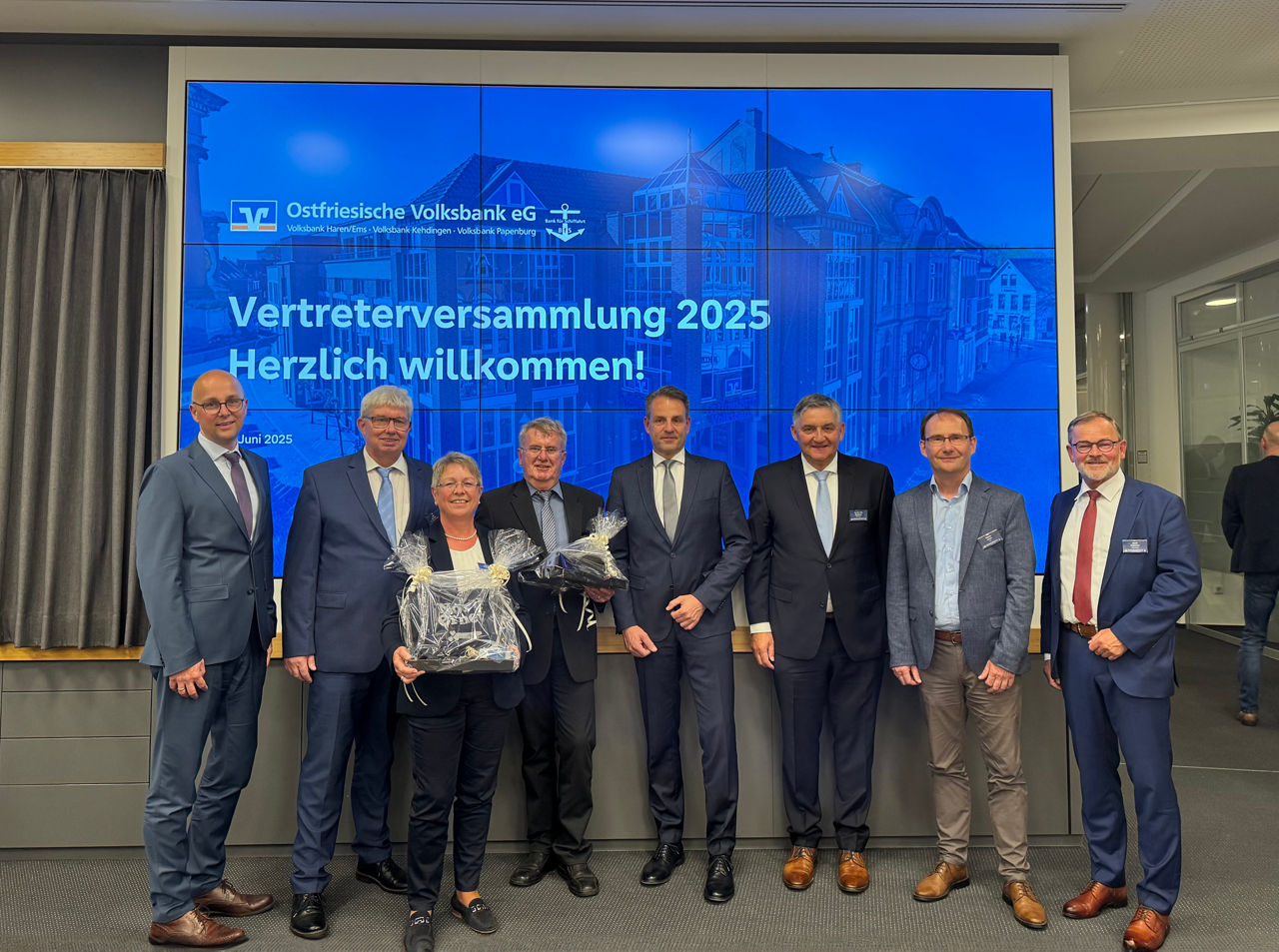 Acht Personen vor Leinwand mit Schriftzug „Vertreterversammlung 2025 – Ostfriesische Volksbank eG“