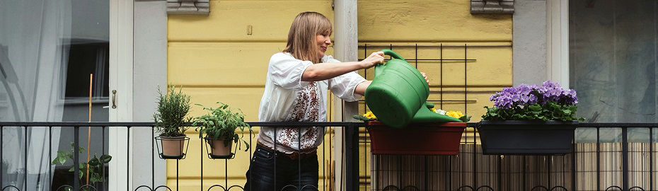 Frau gießt Blumen auf dem Balkon