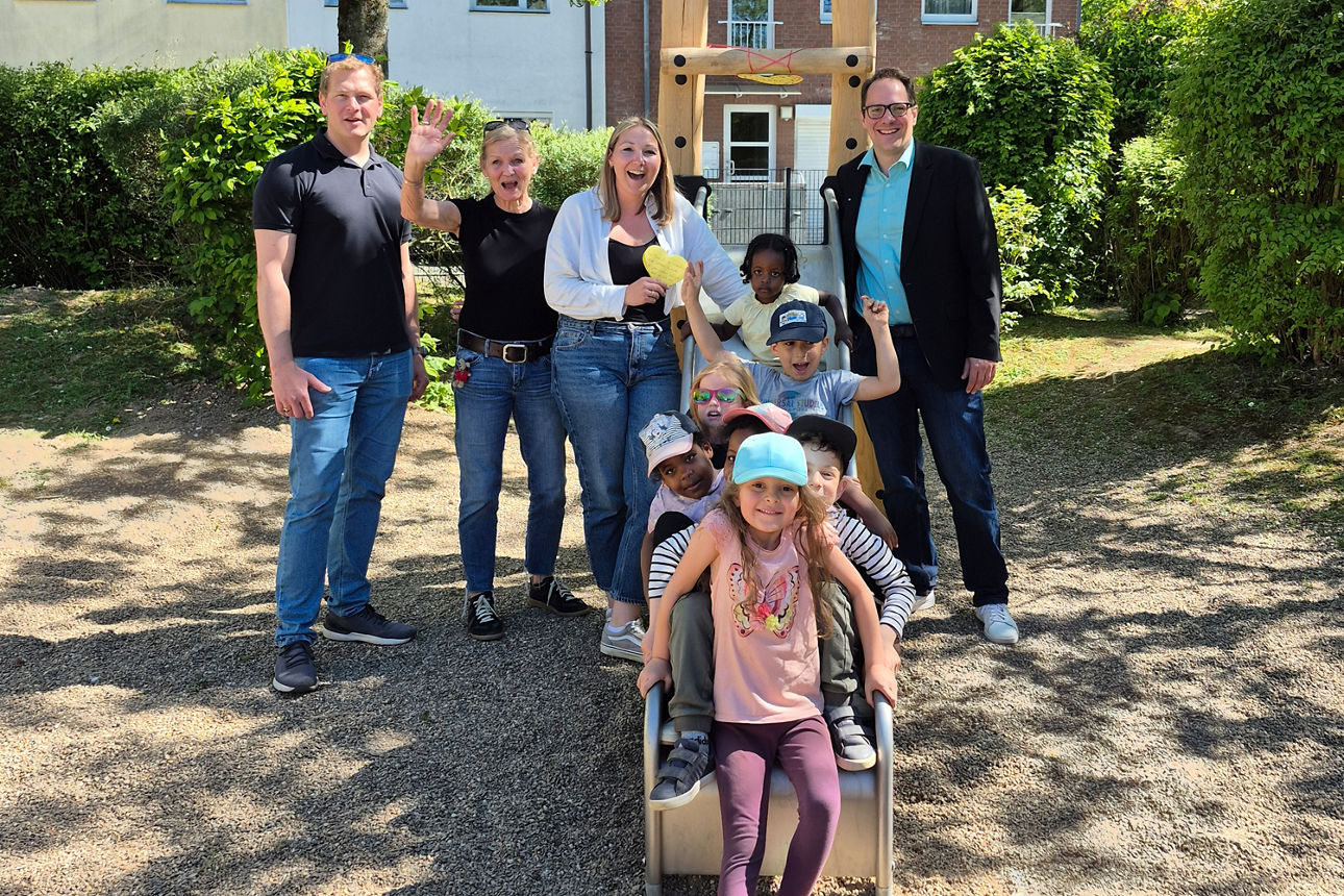 Gruppe mit Kindern auf Spielplatz, gemeinsames Foto bei Freizeit- oder Förderprojekt im Außenbereich.