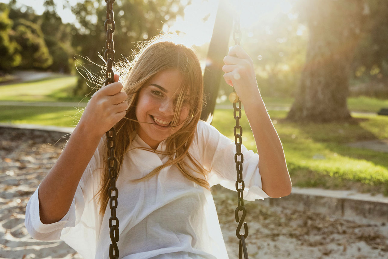Mädchen sitzt lächelnd auf einer Schaukel