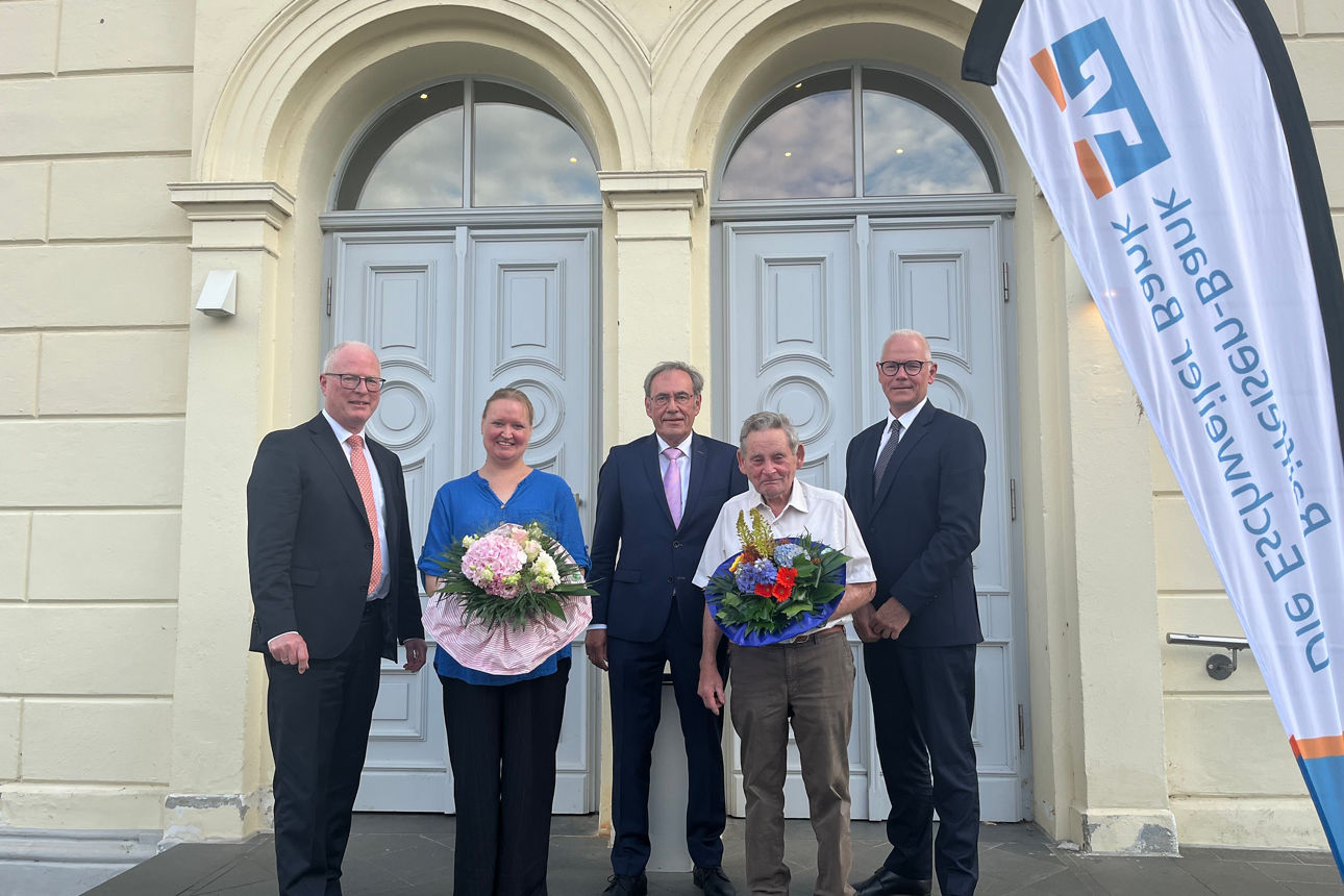 Förmliche Kleidung und ein festlicher Blumenstrauß kennzeichnen ein wichtiges Ereignis in der Bank.