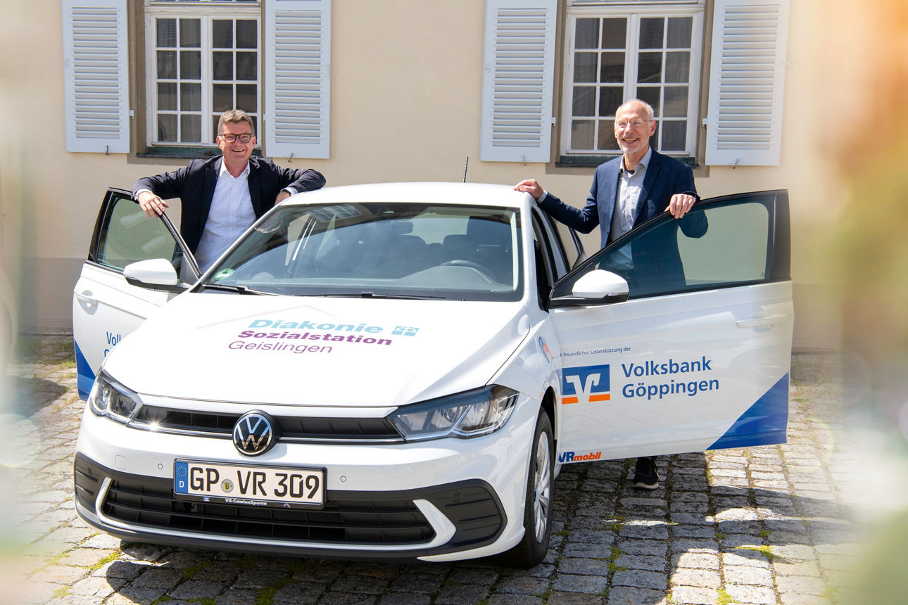 Auto mit offenen Türen und zwei lächelnden Personen