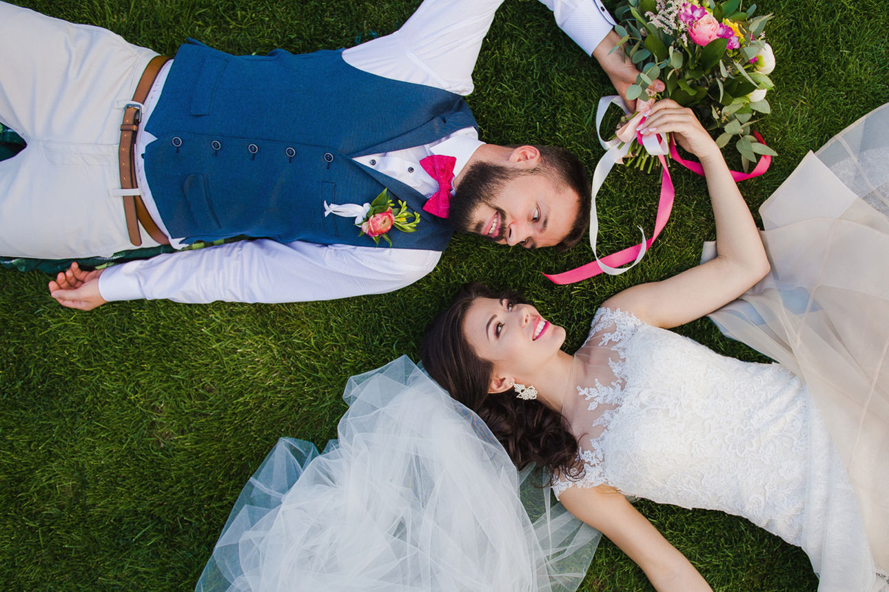 Ein Hochzeitspaar, das lachend auf der Wiese liegt