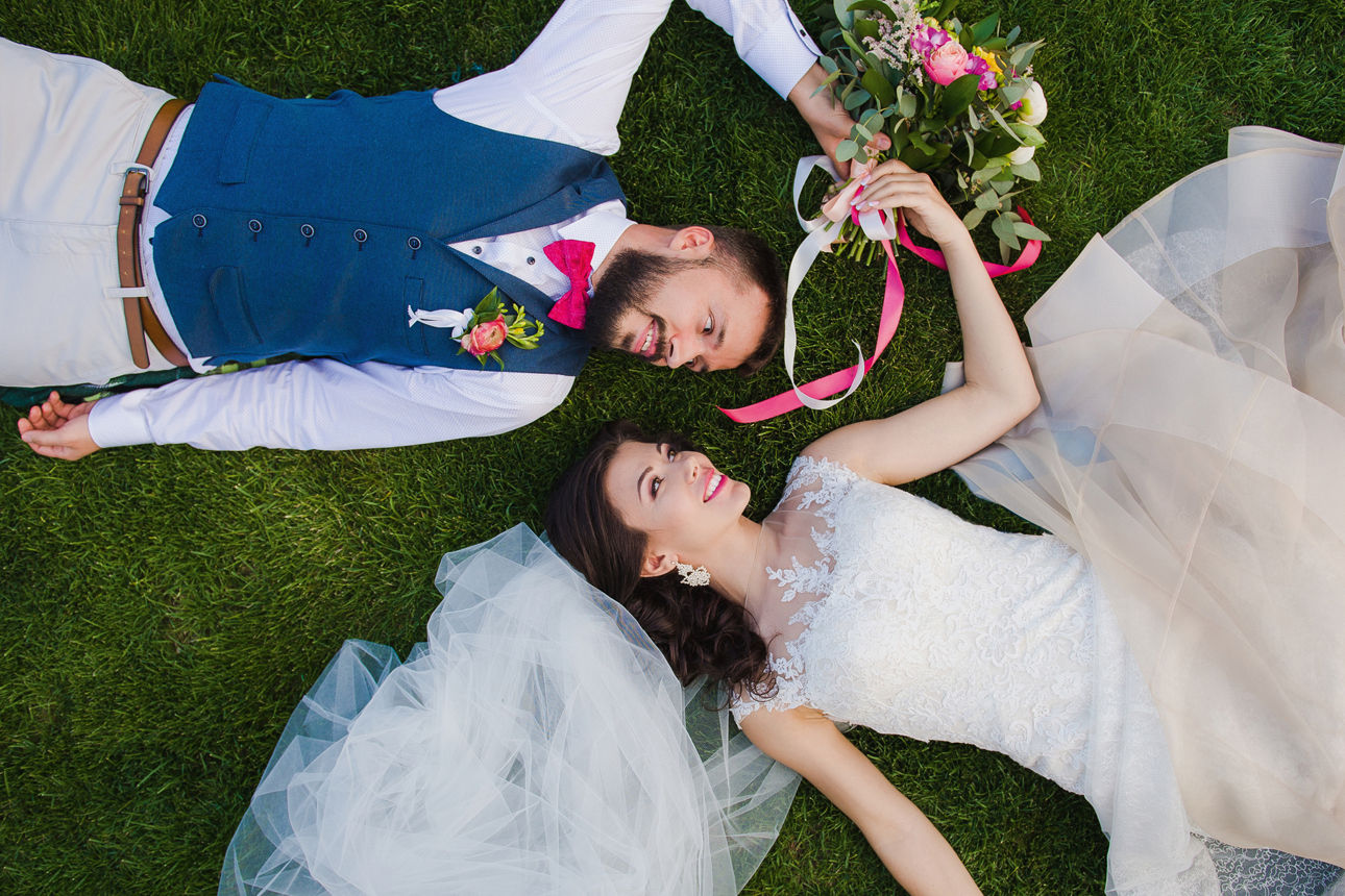 Ein Hochzeitspaar, das lachend auf der Wiese liegt