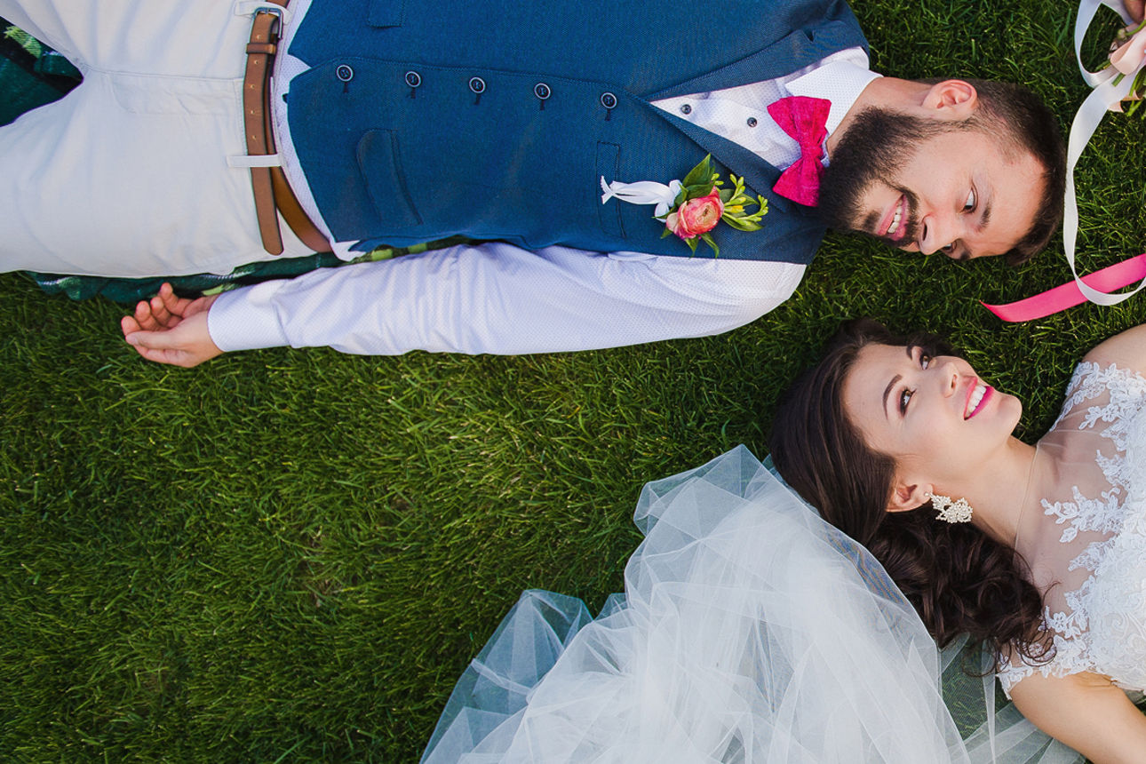 Hochzeitspaar, das lachend auf einer Wiese liegt