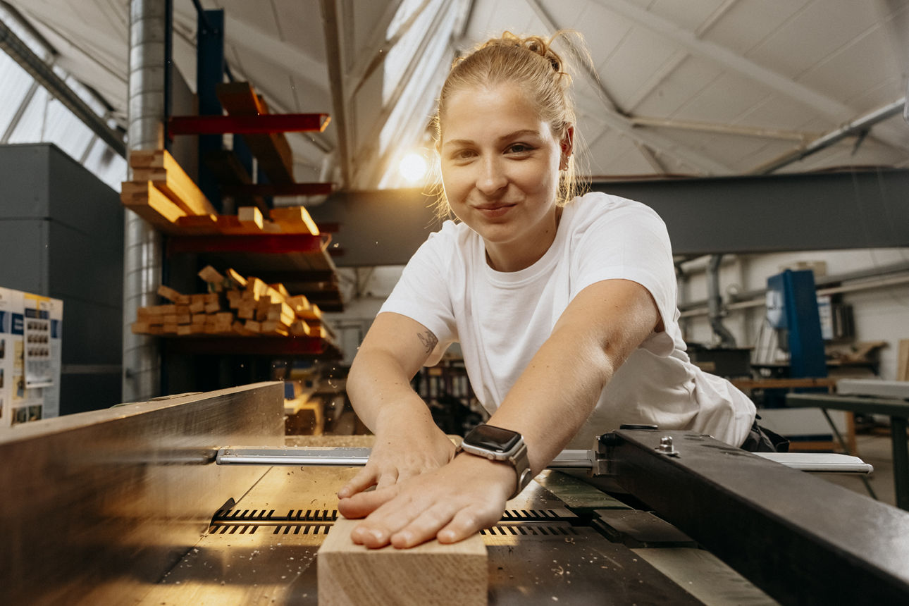 Eine junge Schreinerin arbeitet an einem Stück Holz