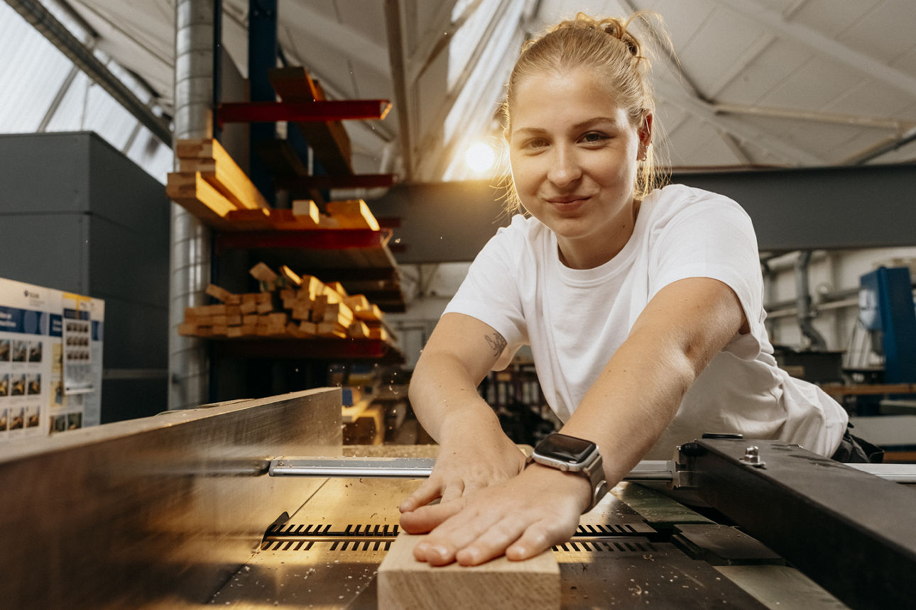 Eine junge Schreinerin arbeitet an einem Stück Holz