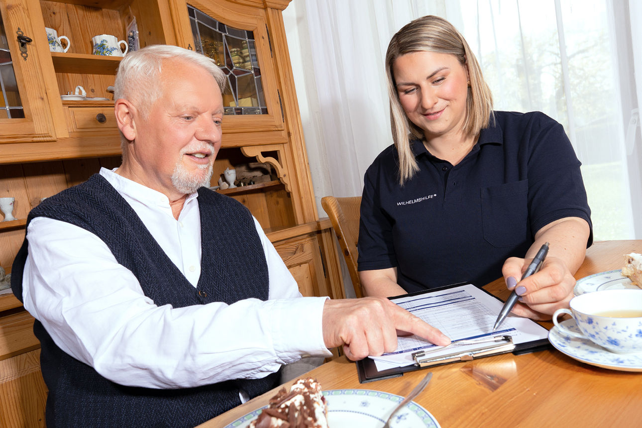 Pflegerberaterin und älterer Herr an einem Tisch