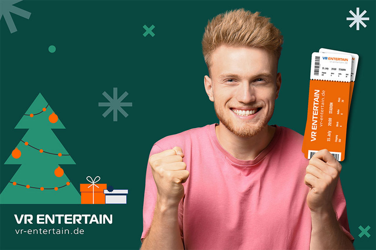 Ein junger Mann freut sich über Veranstaltungstickets. Er steht vor einem weihnachtlichen Hintergrund.