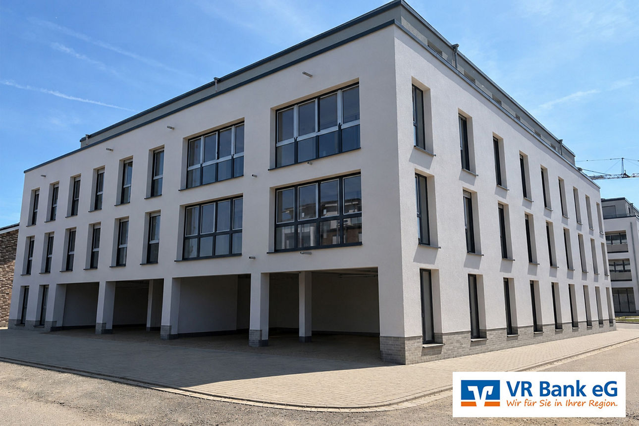 Modernes Bürogebäude der VR Bank eG, Außenansicht mit heller Fassade und großen Fenstern.