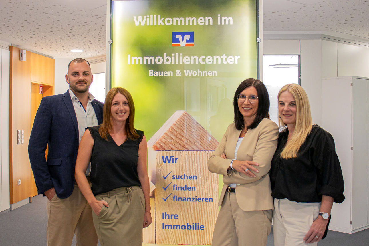 Ein Team von Immobilienfachleuten steht vor einer Ausstellung für ein Immobiliencenter.