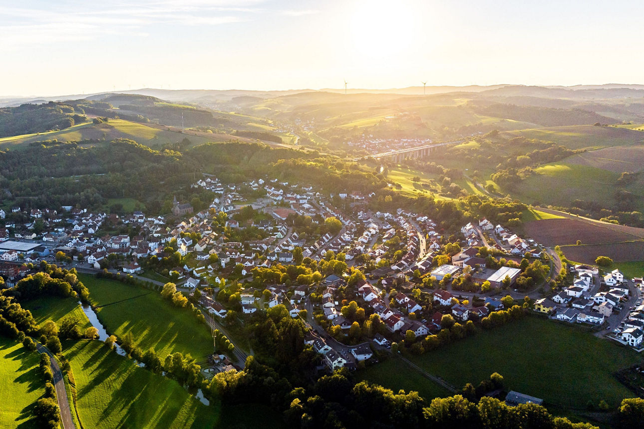 Stadt, eingebettet in sanfte Hügel bei Sonnenuntergang