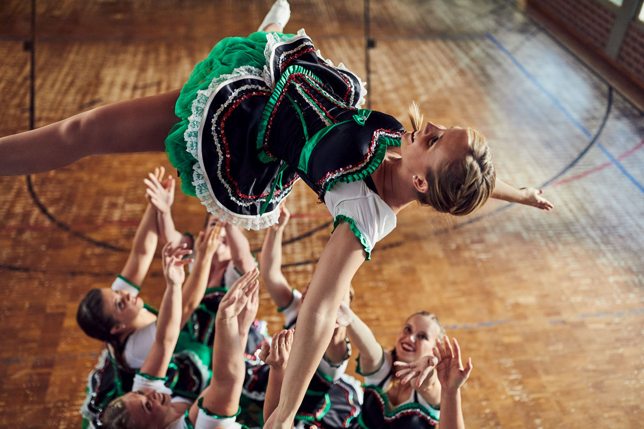 Cheerleaderin wird hochgeworfen