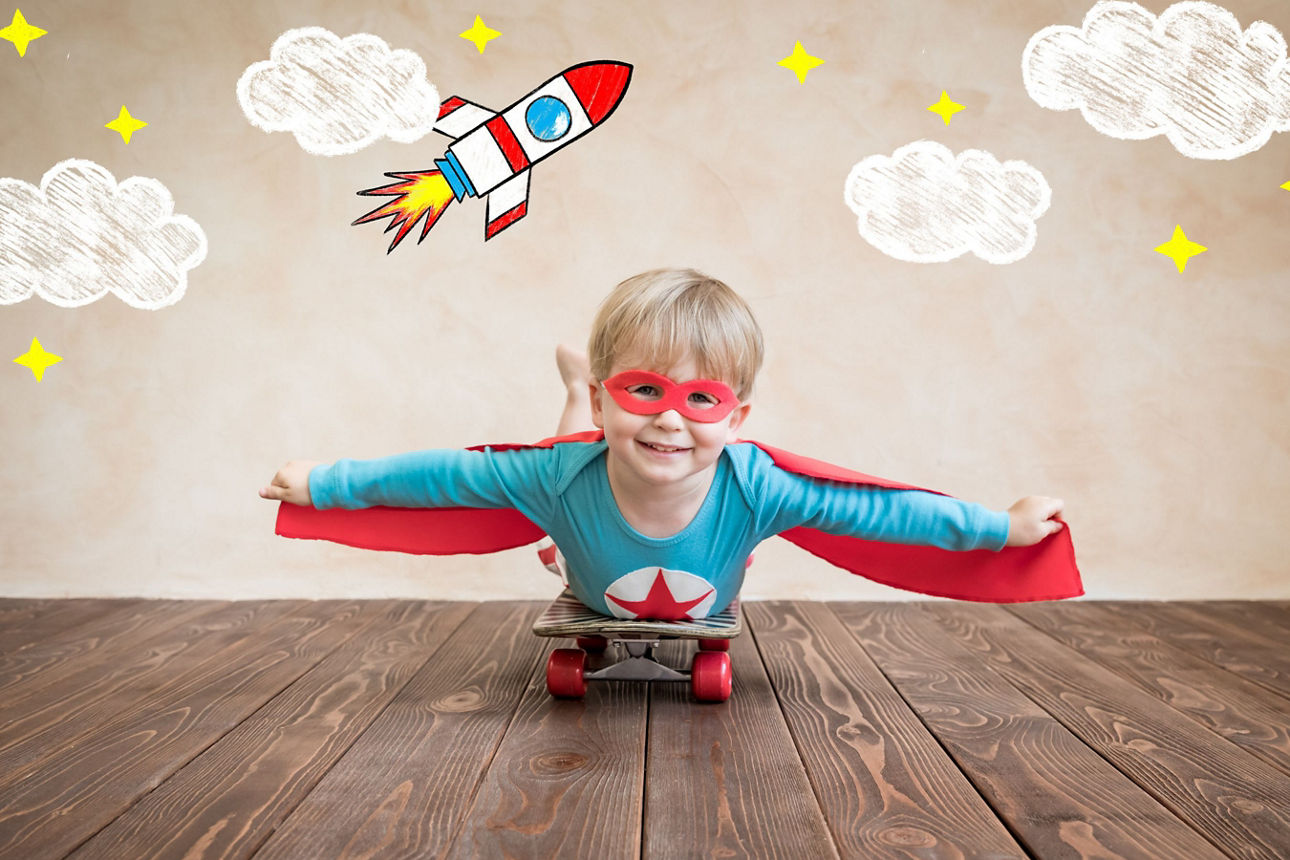 Junge in Heldenanzug auf einem Skateboard über ihm gezeichnete Wolken, Sterne und eine Rakete
