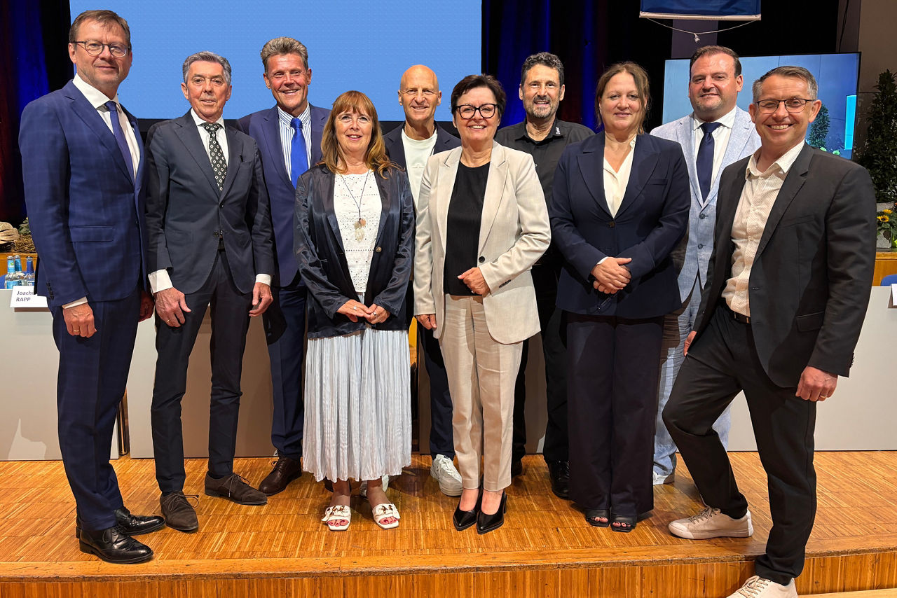 Eine bunte Gruppe von Menschen versammelt sich vor einer Bank