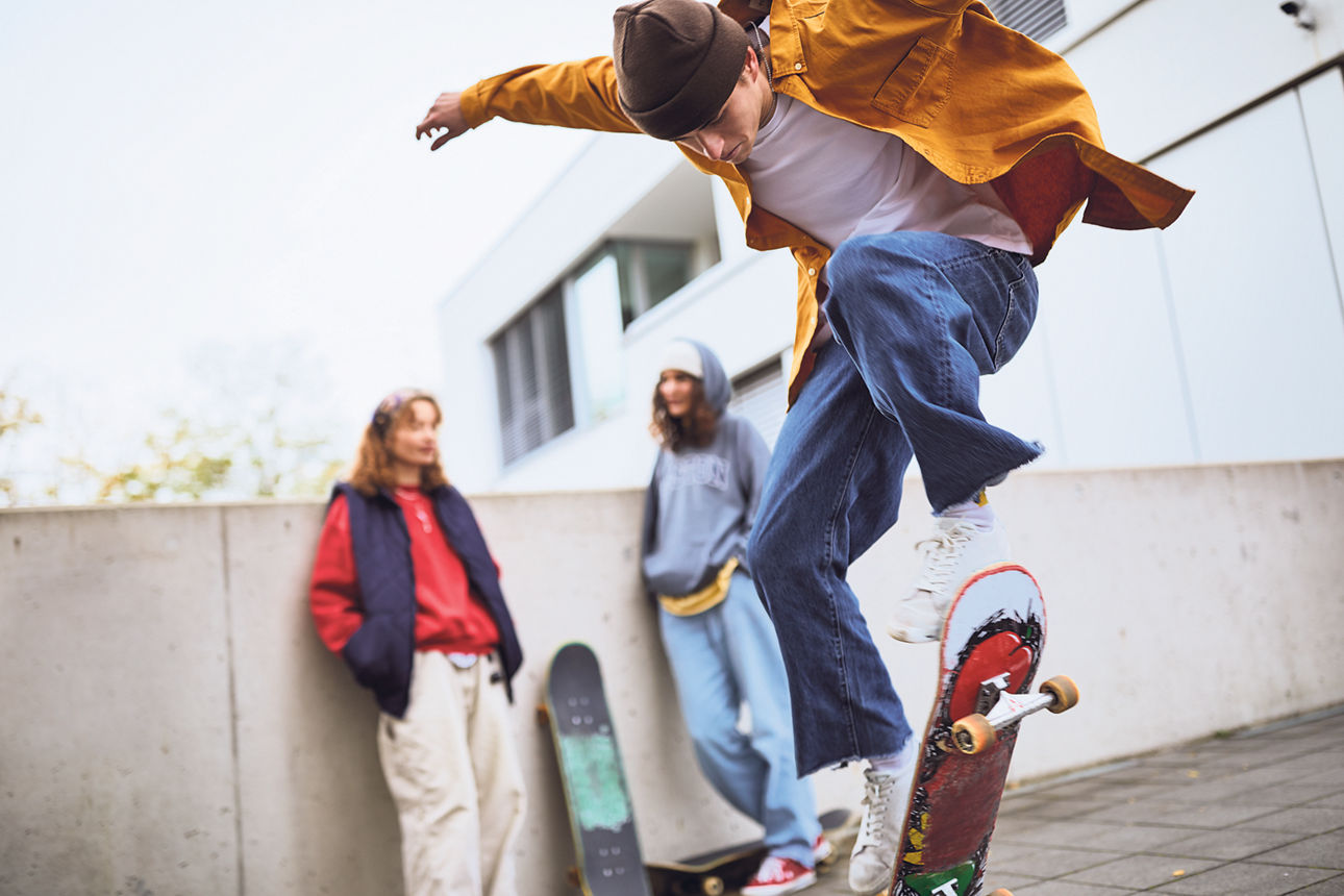 Drei Jugendliche sind mit ihren Sketboards in einem Skatepark