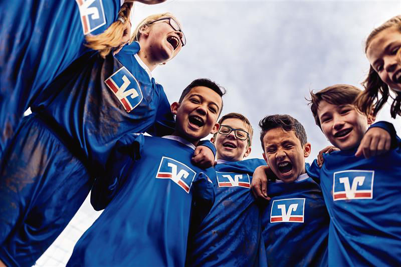 Eine Gruppe von Kindern in blauen Fußballtrikots, die sich umarmen