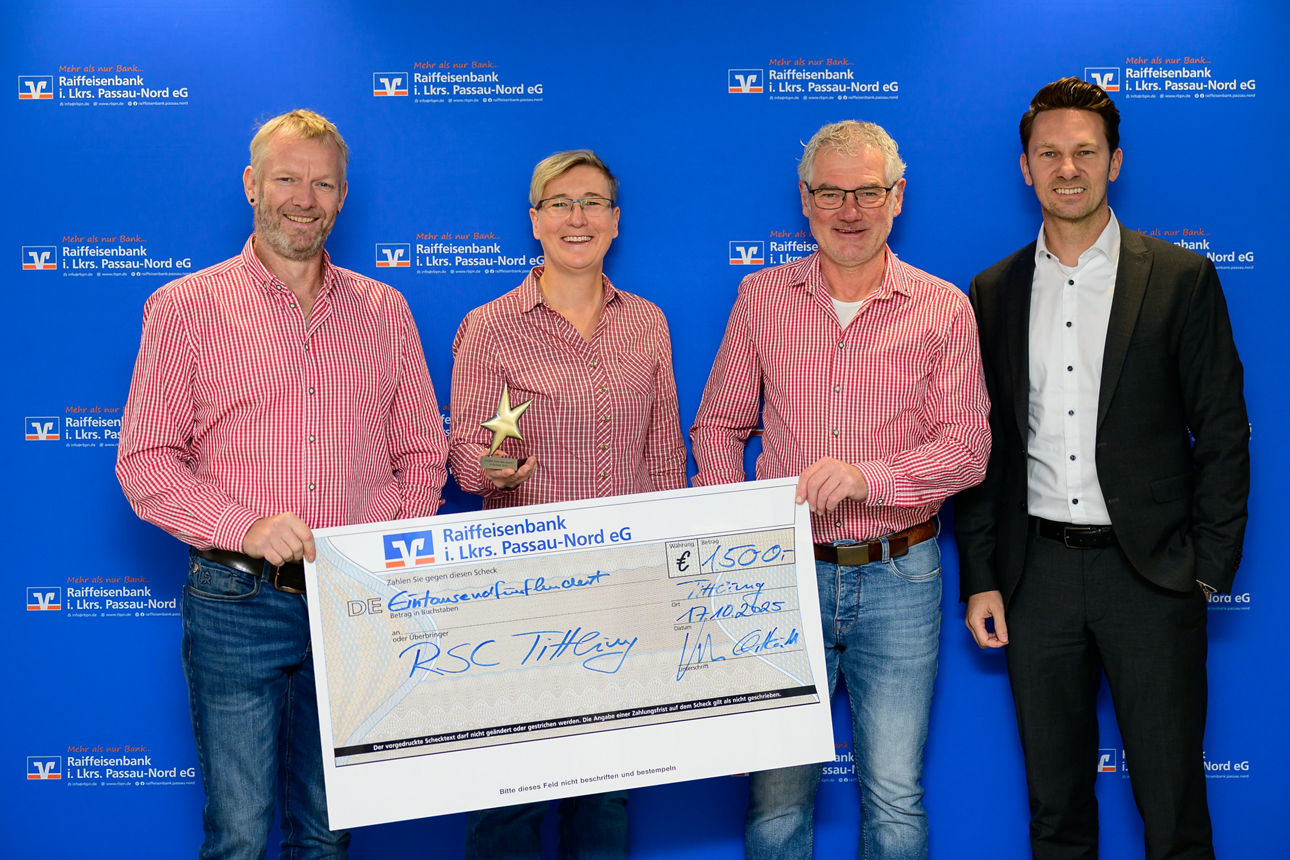 Vier Personen präsentieren stolz einen riesigen Scheck über 1500 Euro von der Raiffeisenbank.